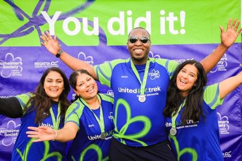 4 participants with medals on and arms high under a you did it sign