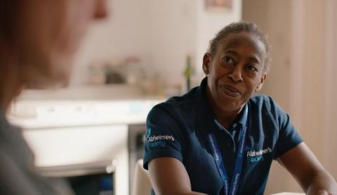 An Alzheimer's Society support worker wearing a branded t-shirt, speaking to someone
