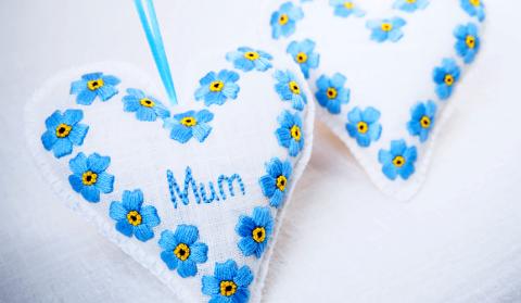 Image shows white cushion heart with blue forget-me-nots and reads 'mum'