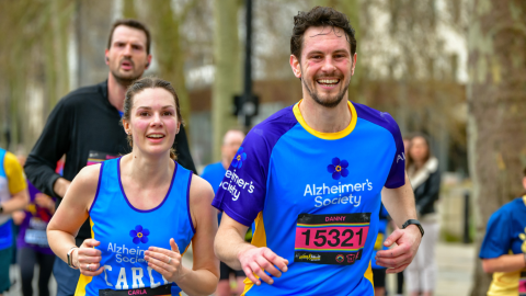 Two Alzheimer's Society runners smiling and running