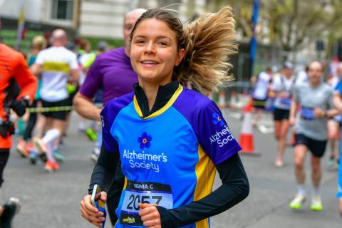 A woman wearing an Alzheimer's Society top, running and smiling