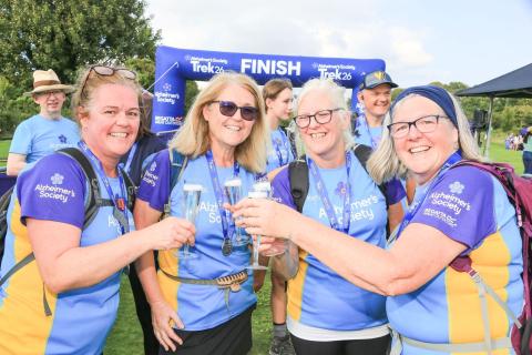 4 trekkers celebrating with fizz on the finish line