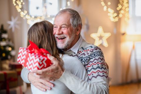 Two people hugging. One is holding a christmas present