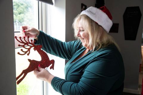 Woman in a window holding a Christmas decoration