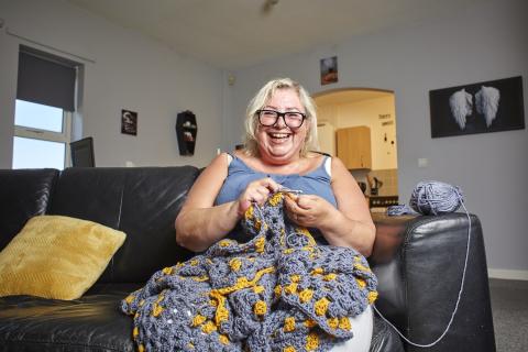 A smiling lady with dementia crochets a large blanket