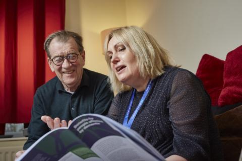 A carer looks through a magazine with a dementia sufferer