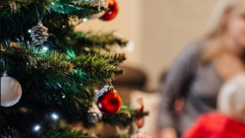 A decorated Christmas tree with out of focus figures behind.