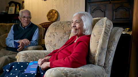 Man and woman sit in front room smiling