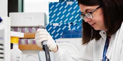 Researcher with glasses and a brown bob in lab doing a test
