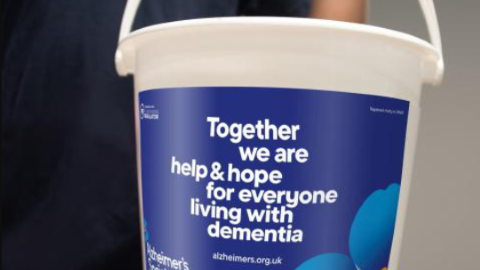 A donation bucket with Alzheimer's Society messaging, 'Together we are the help and hope for everyone living with dementia.'