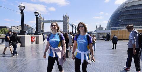 Two women walking in front of Tower bridge.