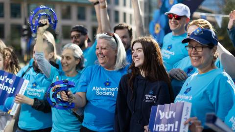 A group of people in Alzheimer's Society merch, cheering with tambourines