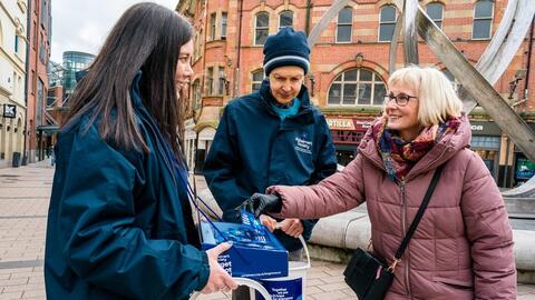 Fundraisers collect donations with donation buckets and forget me not badges