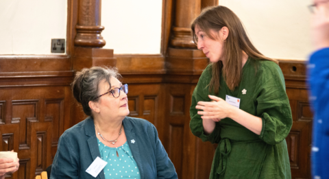 Two women in an event hall talk with each other