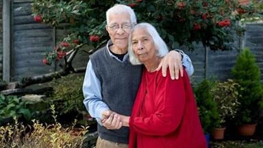 A couple cuddle together in a garden