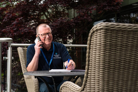 A person sitting down while talking on a phone
