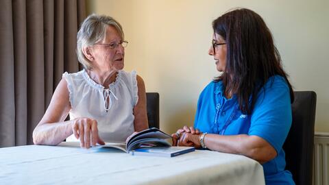 A woman with dementia and a woman working for Alzheimer's Society read through an Alzheimer's Society booklet
