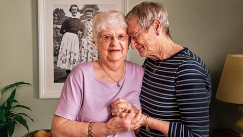 Pauline and Hilary hand in hand standing in their living room