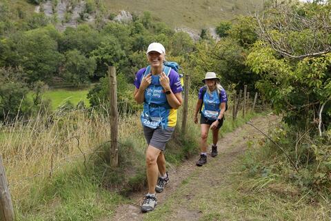Two women walking on a hillside.