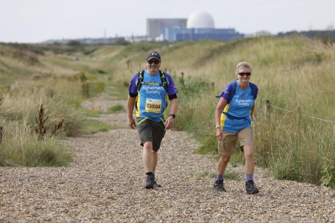 Two people walking on a sandy path.