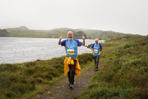 Two men walking on a lakeside path.