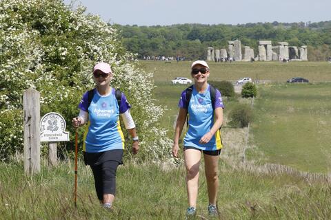 Couple walking with Stonehenge in the background.
