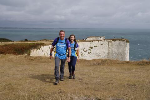 Father and daughter walking along a white cliff with the sea in the background.