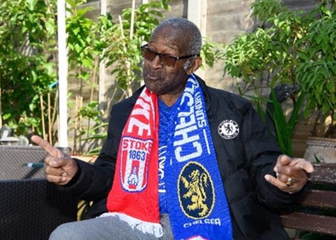 Raymond James sitting in a garden in his Chelsea scarf