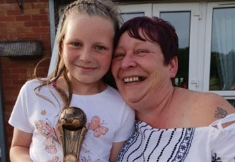 Amanda Griffiths with her granddaughter holding a football trophy