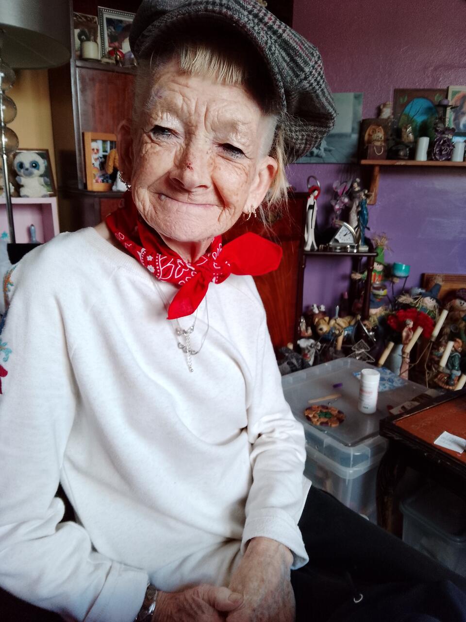 A woman wearing a grey cap, red scarf and white top