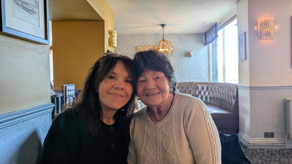 Two women with short brown hair, the woman on the left wearing a dark shirt and the woman on the right wearing a cream jumper