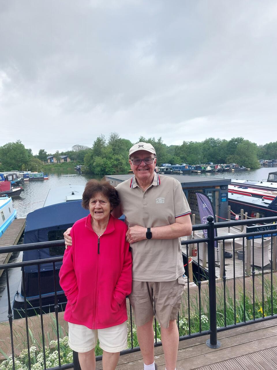 A man with his arm around a woman on a bridge above a river