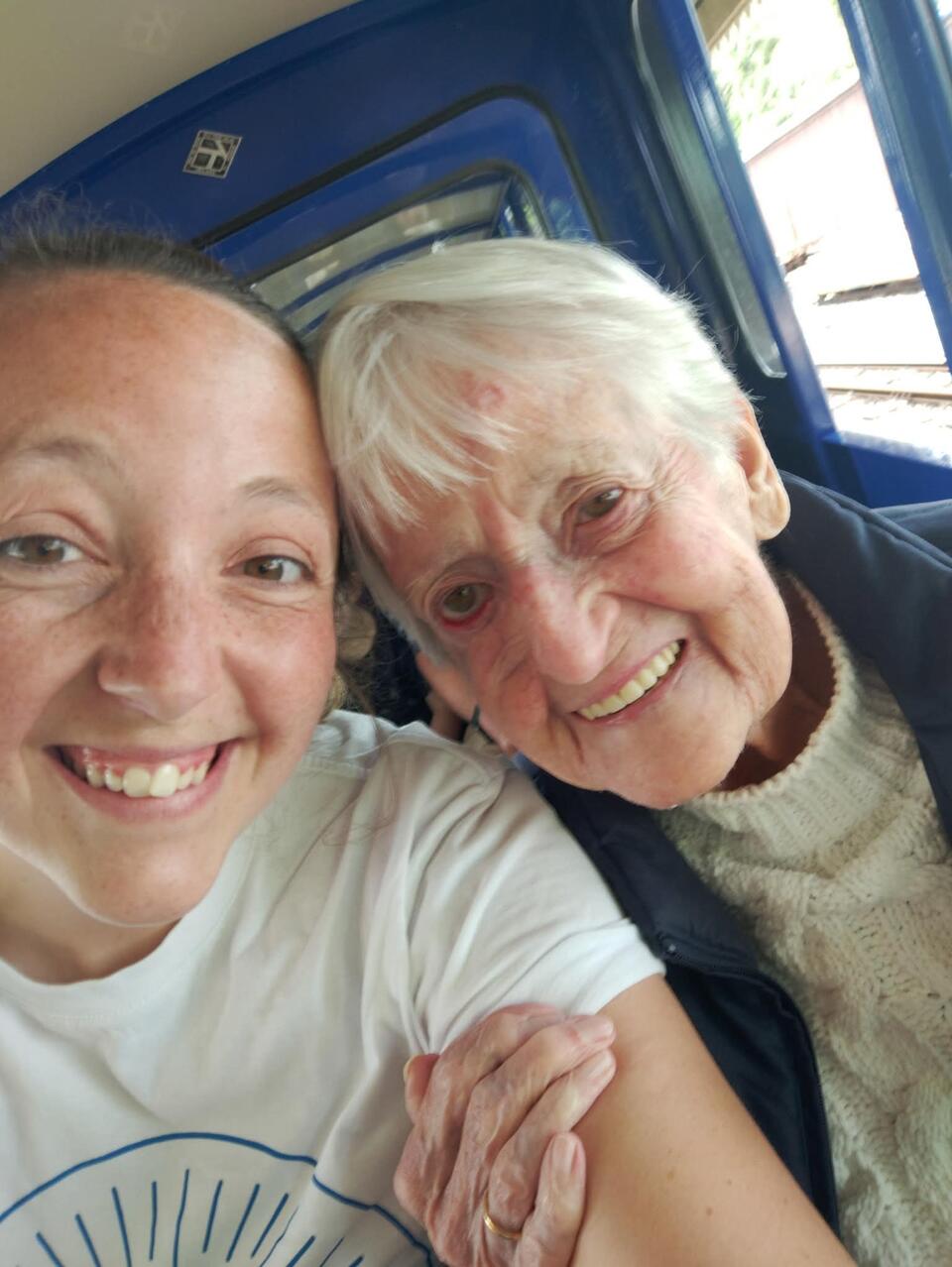 A younger woman taking a selfie with an older woman