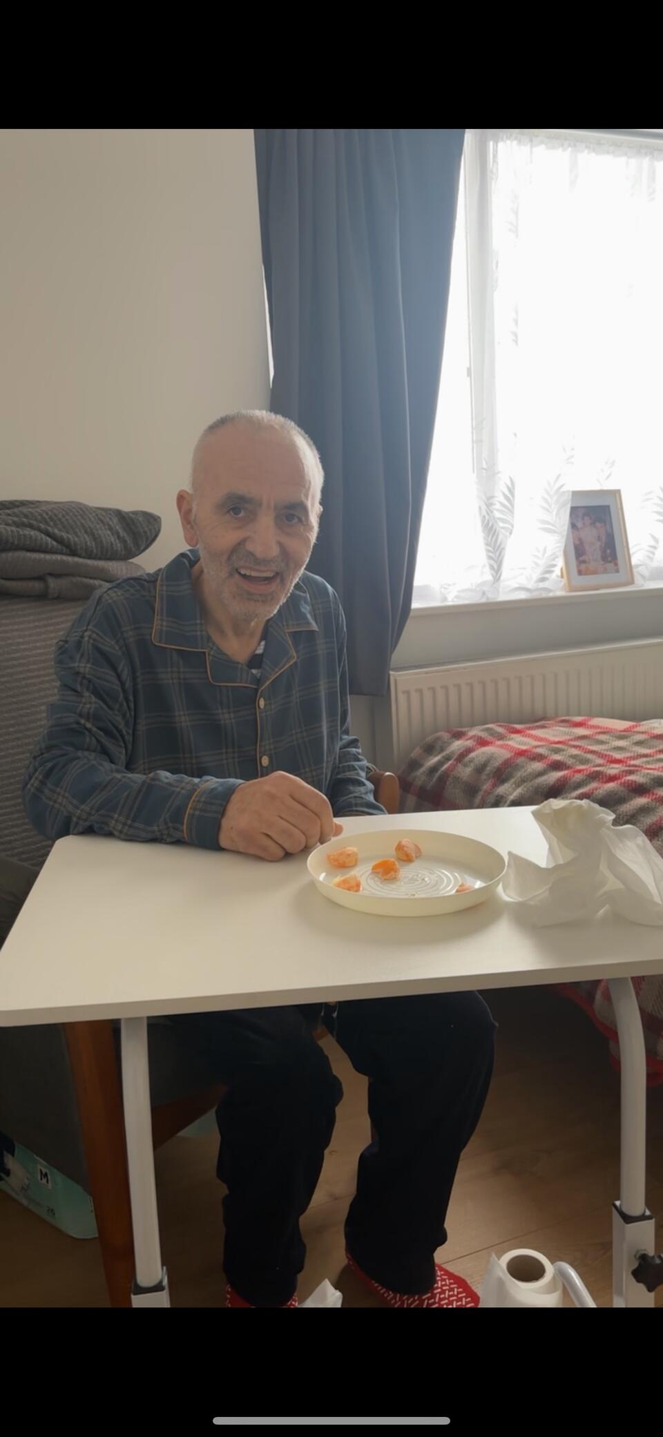 A bald man in a dark check shirt sat at a white table