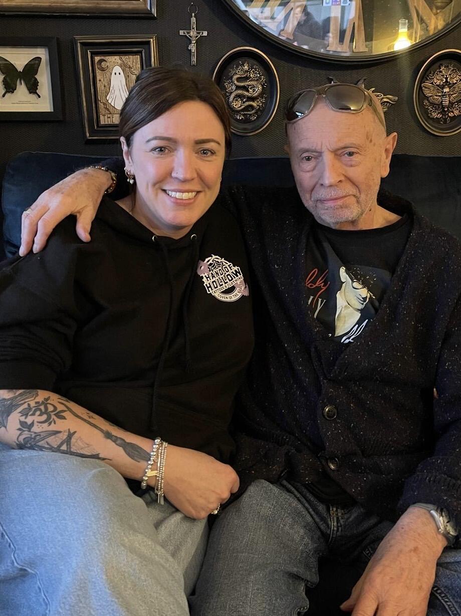 A man sat with a woman with his arm around her shoulders