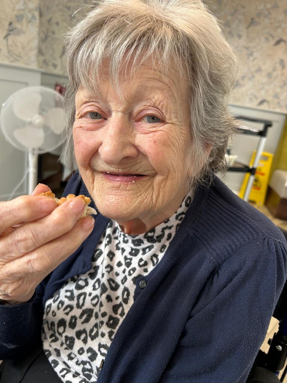 A woman with short grey hair, leopard print top and navy cardigan 