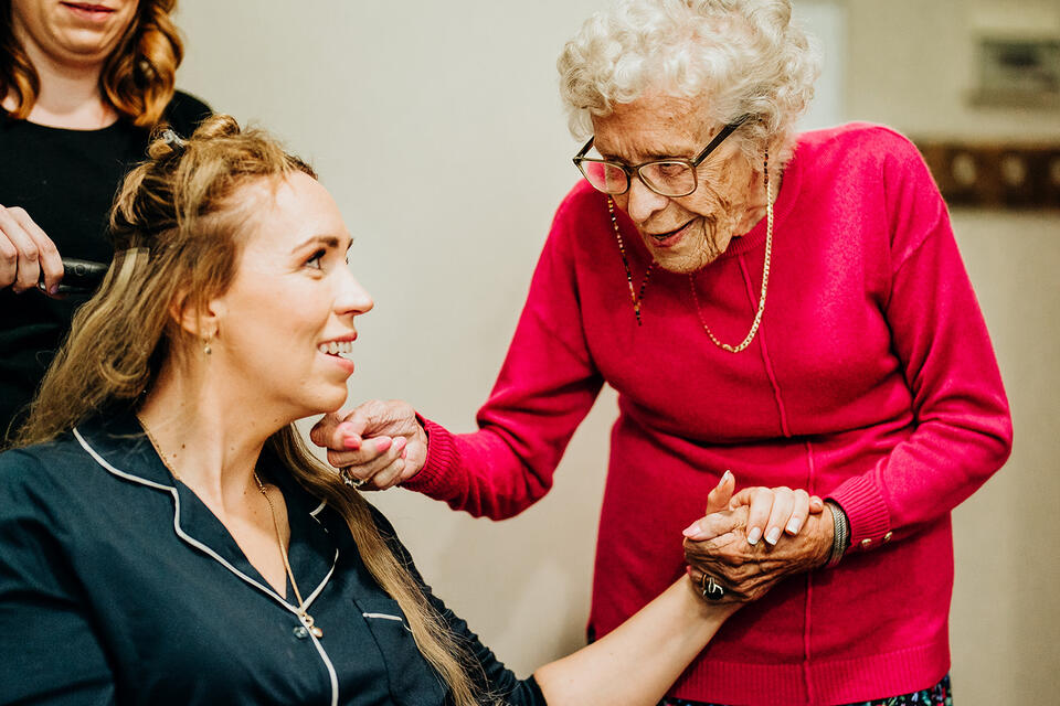 A younger woman having her hair style holding hands with an older lady