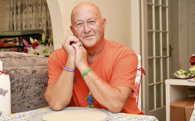 A bald man wearing an orange t shirt sat at a table