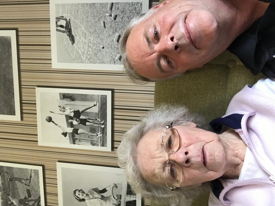 A woman with short grey hair wearing glasses and a pink fleece and a man with grey hair wearing a dark top