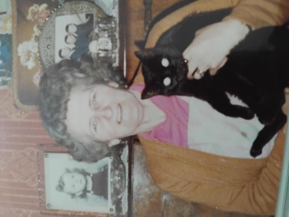 An older woman holding a black cat
