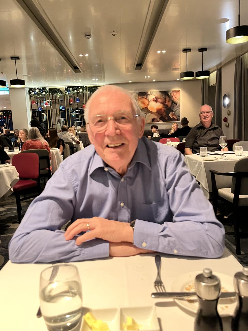 A man smiling, sat at a table in a restaurant 