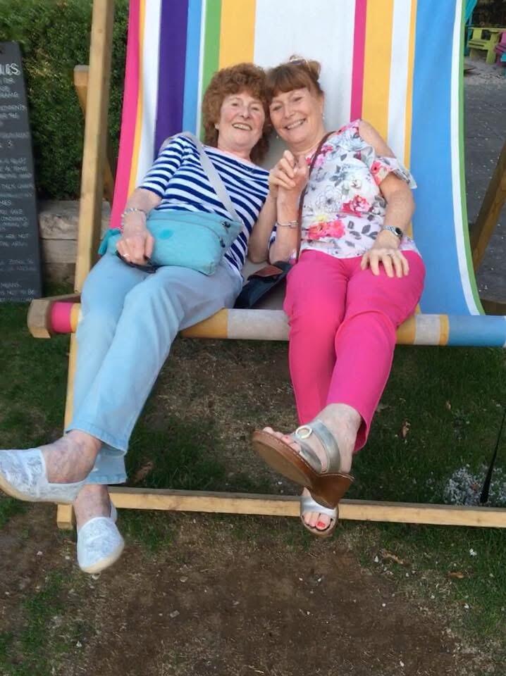 Two women sat on a oversized striped deckchair