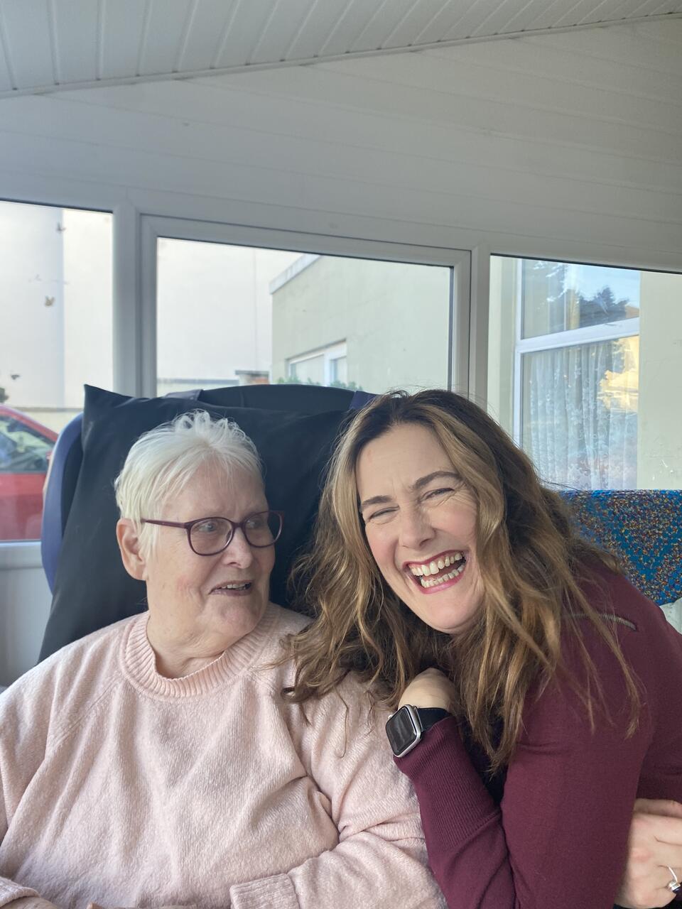 A younger woman crouched next to an older woman sat in a chair