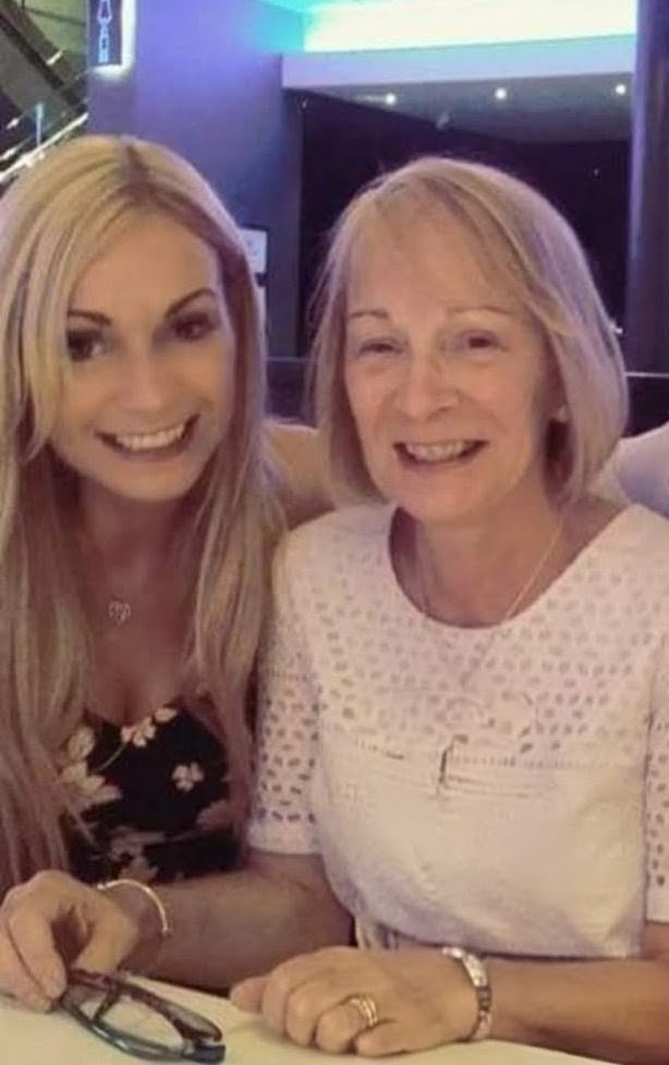 A woman with long blonde hair and patterned top and a woman with short, light hair wearing a white top