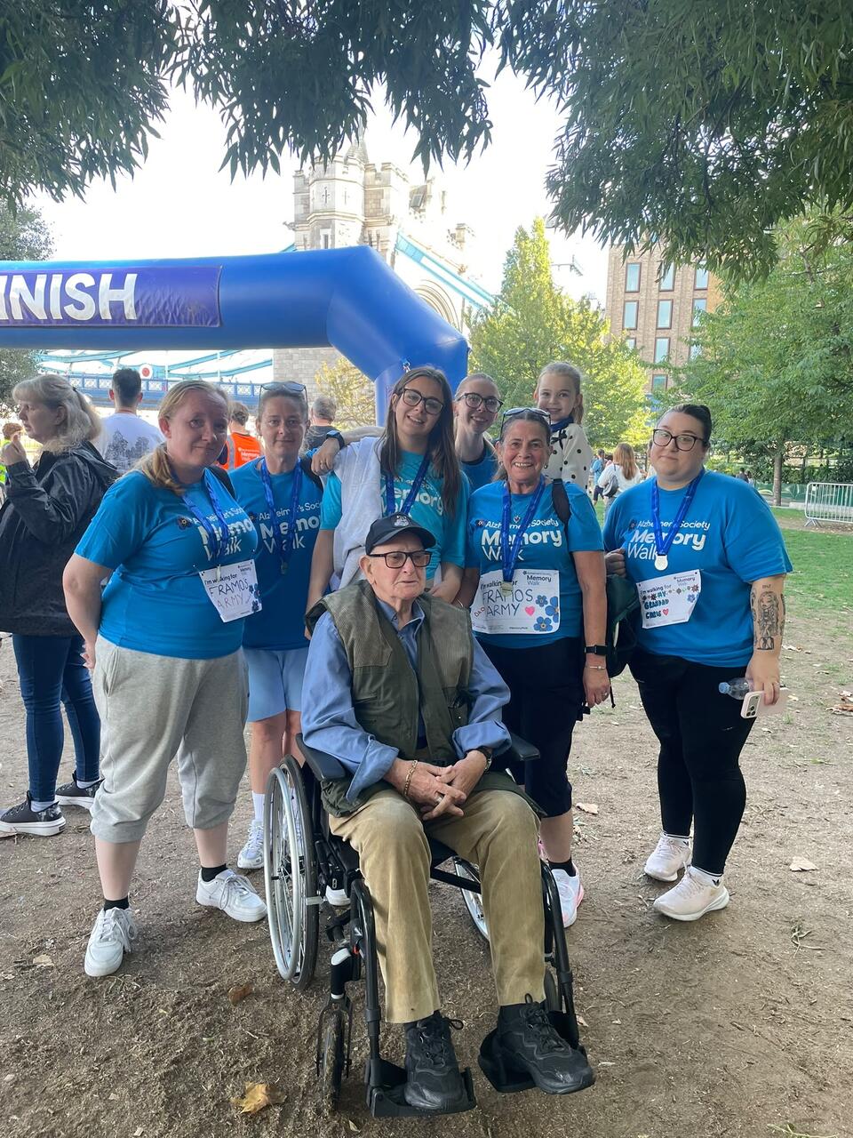 A man in a wheelchair surrounded by five people in Alzheimer's Society t-shirts