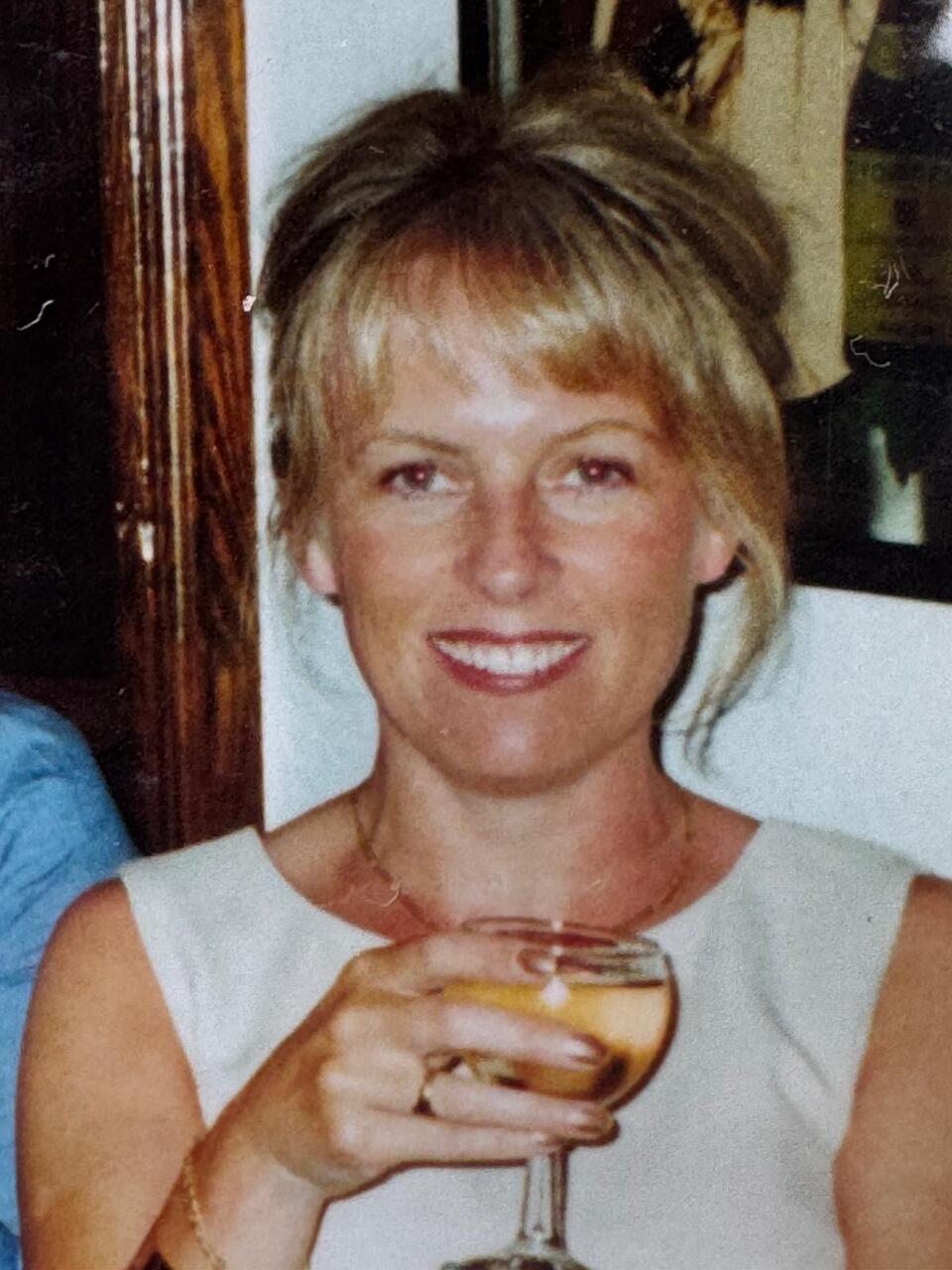 A woman smiling and holding a glass
