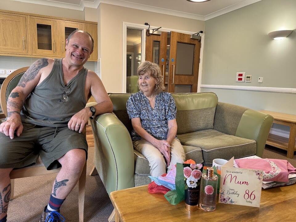 A man sat on a chair next to a woman sat on a green sofa