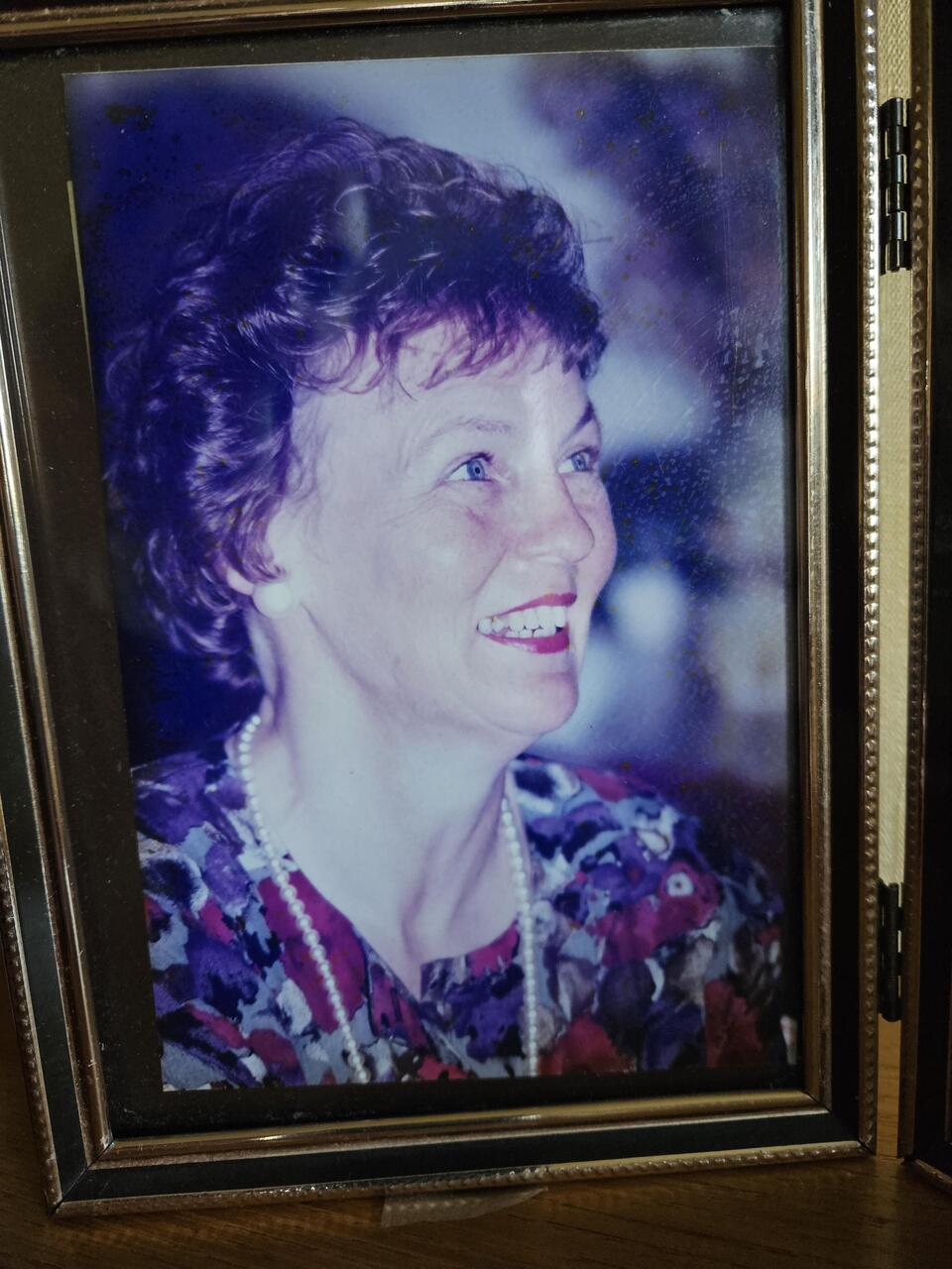 A woman with brown curly hair with red lipstick and a flowery dress