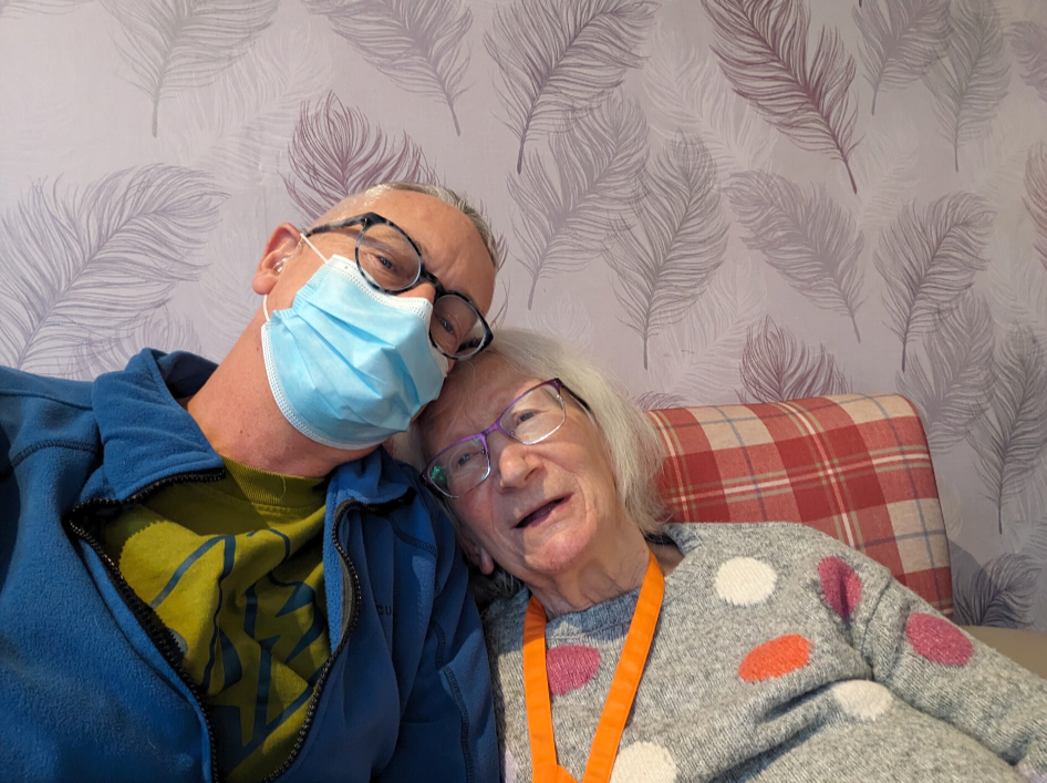 A man wearing a face mask with his head resting on a smiling woman