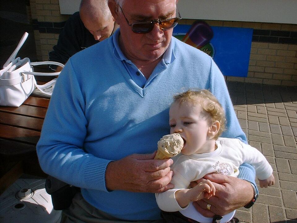 A man holding a baby feeding them an ice cream cone